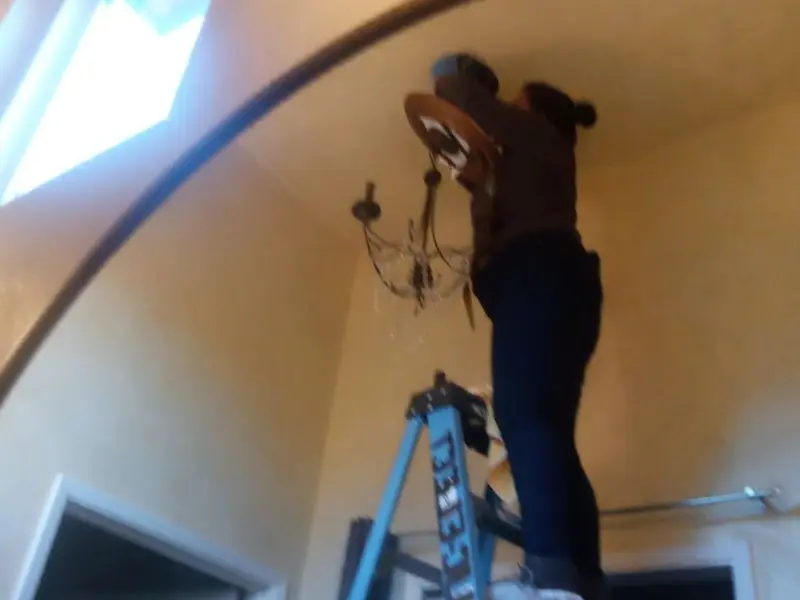 Electrician installing a chandelier in a Farmington residence
